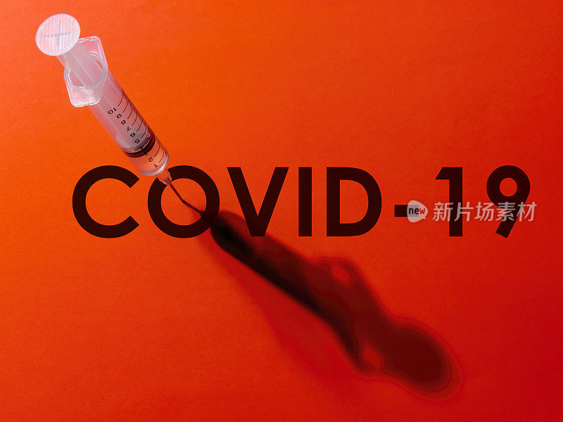 注射器上的针头穿过单词COVID-19 (COVID-19)中的字母“o”的中心。